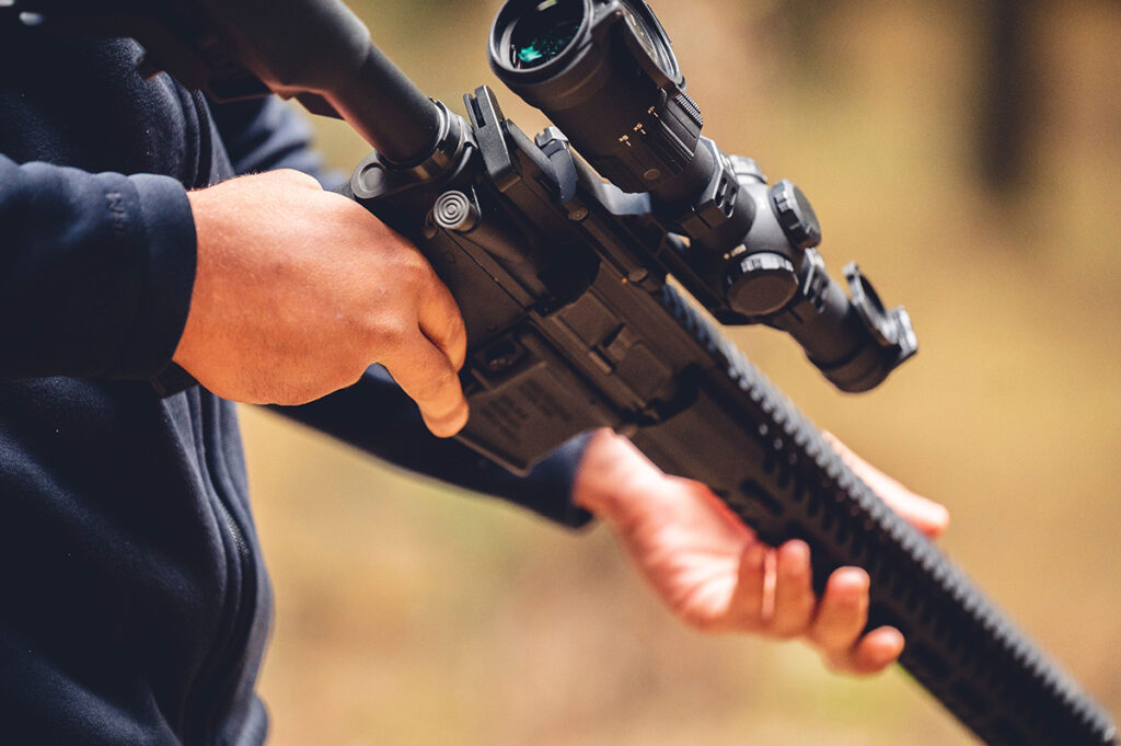 Hunter holding rifle with scope checking for jamming